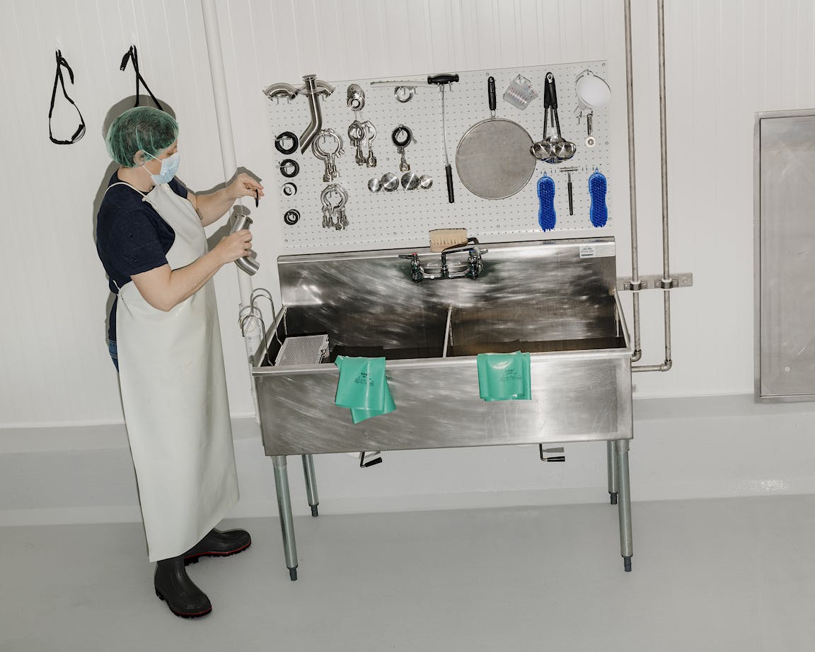 A person stands next to an industrial sink.